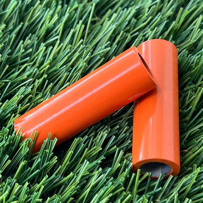 Two shiny orange ZUCA cart wheel spacers made of durable plastic are lying on a green surface.